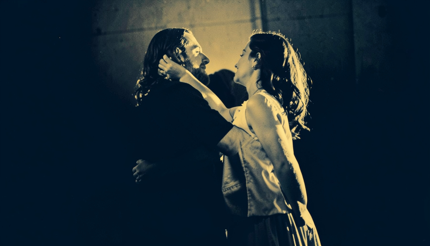 Duotone image of a couple in a dramatic dance pose, warm amber and dark navy palette