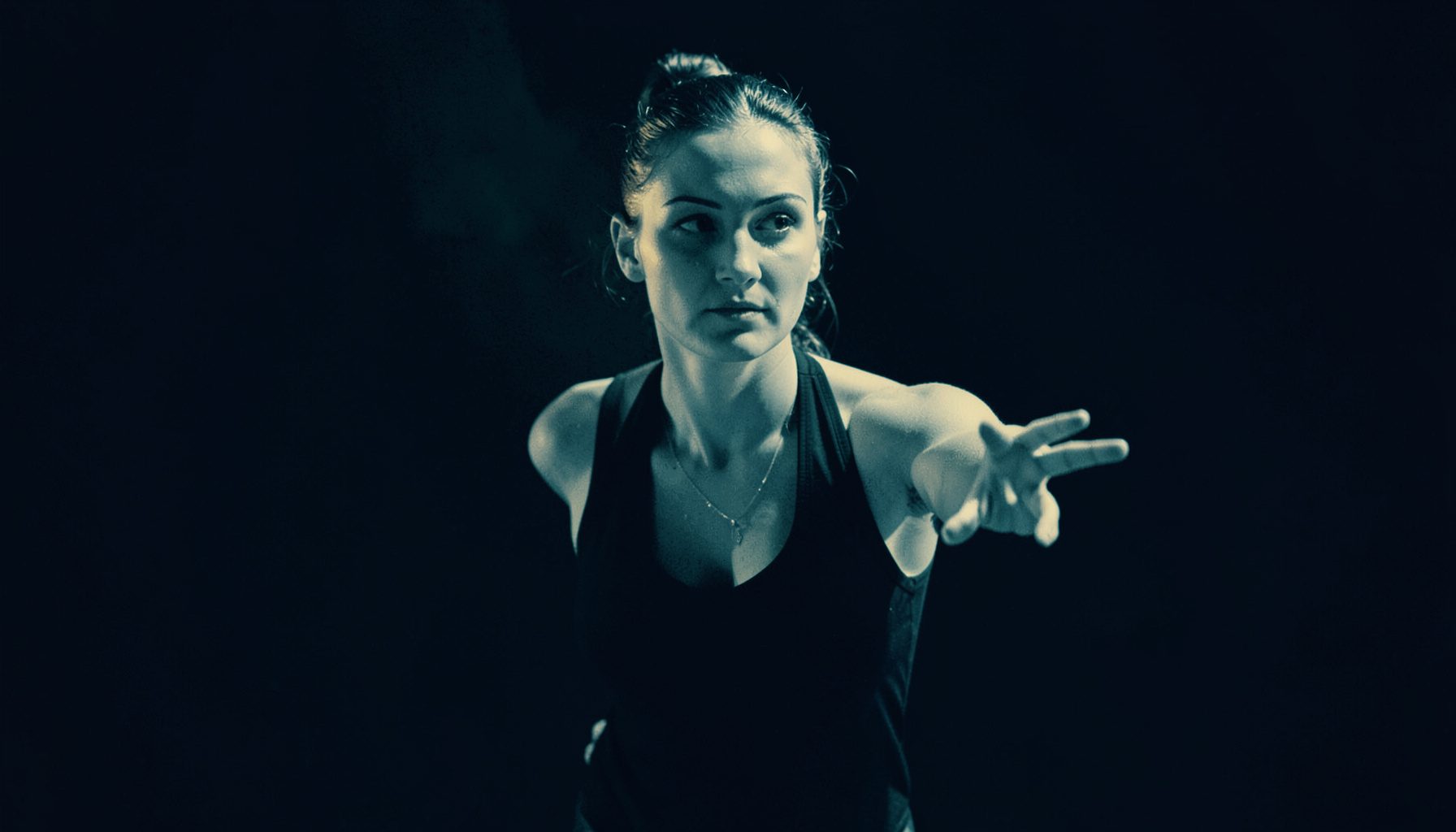 Duotone portrait-style image of a female dance instructor, amber light against dark navy backdrop